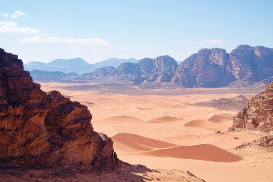 Aerial view of desert landscape from the top of a mountain, with sandy dunes and distant rock formations