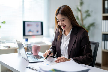 A woman is sitting at a desk with a laptop and a notebook