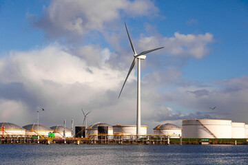Onshore oil storage near the seaport and wind turbines on the shore.