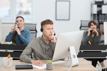 Salesman talking to client via headset at desk in office