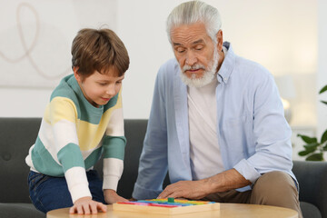 Obraz premium Grandpa and his grandson playing with math game Times table tray at home