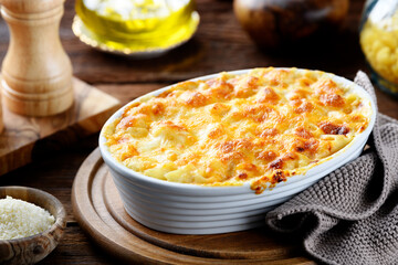 Homemade Fresh Baked Creamy Macaroni and Cheese, Pasta in a Baking Dish. Wooden background