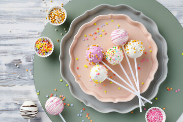 Various cake pops decorated with white and dark chocolate, sprinkled with sugar confetti, top view