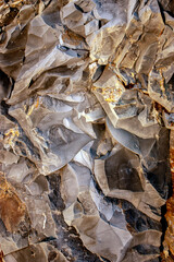 View of a part of a sedimentary rock. Yellow-brown abstract background. Texture of natural stone. Brown-yellow background for a banner. Rough drawing of a rock layer.