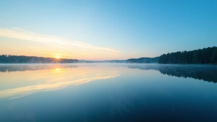 Fototapeta premium Stunning sunrise reflection on a tranquil lake with blue sky and distant trees