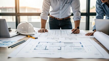 An engineer discussing plans over a large blueprint with diagrams of reactor components spread out on a table highlighting a collaborative effort.