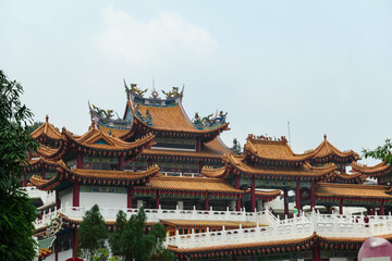 Intricate architecture of Chinese Thean Hou Temple. Roof is adorned with vibrant colors, intricate patterns, decorative figures. Rows of red lanterns hang above entrance. Festive touch. Goddess of Sea