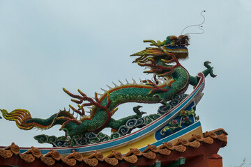 Vibrant dragon sculpture perched atop Chinese Thean Hou Temple roof. Statue intricate details like scales and claws. Festive atmosphere in traditional landmark. Kuala Lumpur, Malaysia, Southeast Asia
