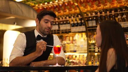 Bartender serving mixed vodka Cosmopolitan red cocktail decorated with flower for beautiful guest at luxurious counter bar perfect vibrant color presentation highlight atmosphere nightclub. Vinosity.