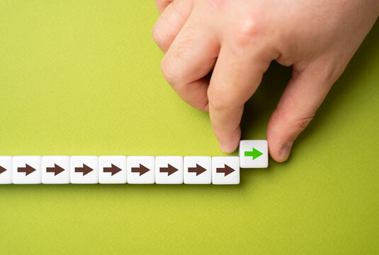 A hand makes a path out of blocks with arrows. The concept of moving forward and continuing progress. Strategic planning, forward momentum, and the continual pursuit of growth and improvement
