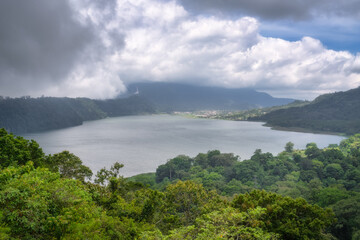 A stunning landscape features a tranquil lake among lush hills, beneath a picturesque sky, perfect for nature lovers and outdoor enthusiasts seeking adventure, Bali, Indonesia