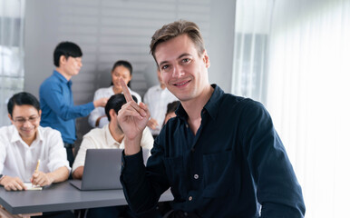 Confidence and happy smiling businessman portrait with background of his colleague and business team working in office. Office worker teamwork and positive workplace concept. Prudent