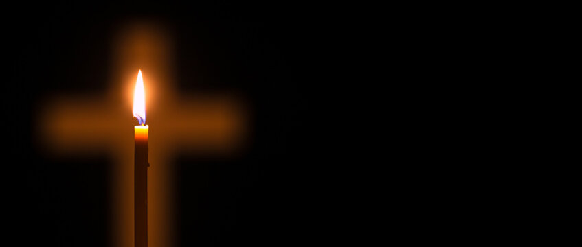 Candle is lighting and glowing through hole in shape of Christian cross among darkness. Concept of Christianity, religiosity and sincere faith. Copy space