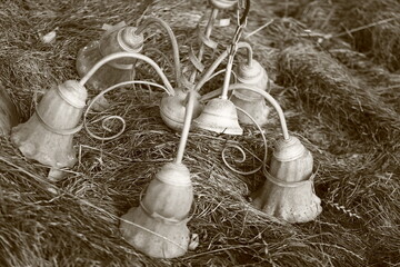 forgotten old chandelier in lying grass, black and white photo sephia