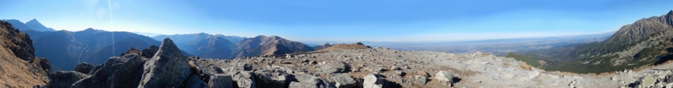 Panorama of Tatras, Tatra Mountains with rocky hill massif Giewont, Kasprowy Wierch, Kasper Peak, Czerwone Wierchy, Red Peaks, rocky mountain trail and blue sunny sky. Topic: Tatra National Park