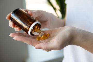 Woman pouring dietary supplements into her hand. Woman taking omega 3, omega 6, omega 9, fish oil...