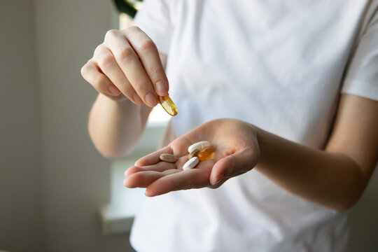 Сlose-up of a woman's hands with various pills and supplements. Woman taking omega 3, omega 6, omega 9, fish oil capsules, vitamin D, vitamin C, magnesium. Take vitamin for treatment for skin, hair.