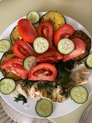 Baked fish and fresh vegetables on a plate. Healthy lunch or dinner