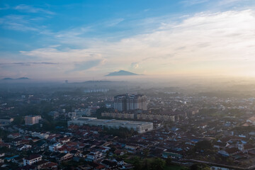 Hazy, atmospheric view of Malacca city in Malaysia, Southeast Asia. Mountain Mount Ledang in the background. Haze obscures details, creating a soft, almost dreamlike atmosphere. Morning moments
