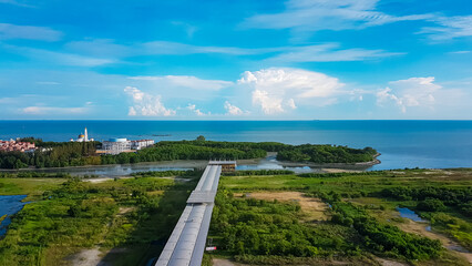 Fototapeta premium Aerial view shows long, straight walkway or bridge called Jetty extending towards sea in Melaka, Malaysia, Southeast Asia. Overlooking the Malacca Strait. Shoreline, with mosque's white minaret