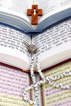Bible, Quran and Torah. Concept of interfaith dialogue.  Christianity, Islam and Judaism, the three monotheistic religions. Religious symbols : christian cross, dreidel, prayer beads.