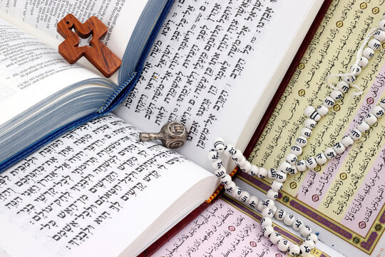 Bible, Quran and Torah. Concept of interfaith dialogue.  Christianity, Islam and Judaism, the three monotheistic religions. Religious symbols : christian cross, dreidel, prayer beads.
