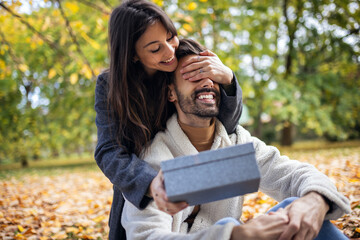 Girlfriend surprises her boyfriend with gift on Valentines day while they are on the picnic in the park.