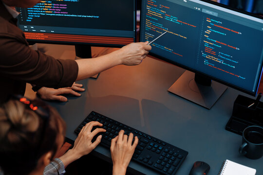 Top view of IT developers discussing with point to intelligent website development coder system running data online two screens information technology at neon light room at modern office. Infobahn.
