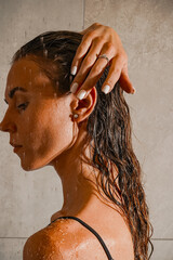 A close-up of a woman with wet hair and water droplets on her skin, exuding freshness and confidence. The soft lighting enhances her natural beauty and grace.