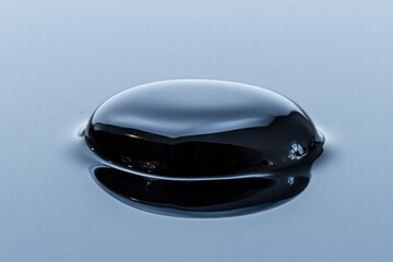 Close up view of a single black oil drop reflecting light in a clear environment during daylight. Generative AI