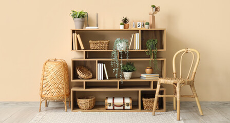 Bookshelf with modern wi-fi router and plants near beige wall in room