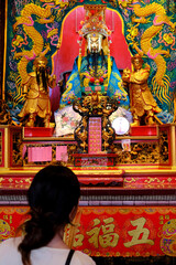 Fototapeta premium Guan Di chinese Temple in Chinatown. Offerings and prayer to the temple deities. Asian woman praying. Kuala Lumpur. Malaysia.