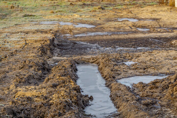 ruts in the frozen mud at the entrance to the construction site. frozen water, ice in a puddle.