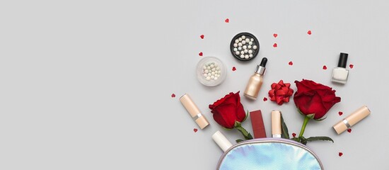 Cosmetic bag with makeup products and red roses on grey background with space for text. Valentine's...
