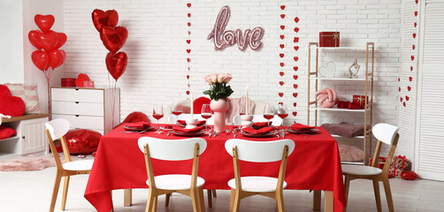 Table setting decorated for Valentine's Day with pink roses and candles at home