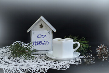 Calendar for February 2: numbers 02, name of the month February on a decorative calendar, white napkin, cup