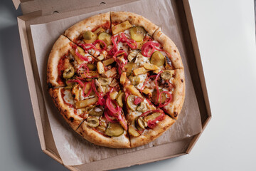 pizza with pickled onions and cucumbers in a cardboard box. Pizza delivery