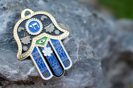 The hamesh hand or hamsa hand is a popular motif in Jewish jewelry. Religious symbol on a rock.