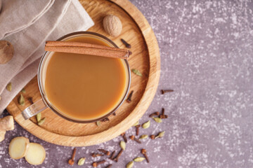 Glass cup of tasty masala tea with different spices on grunge background, closeup