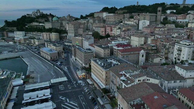 The video highlights the panoramic beauty of Ancona, Italy, showcasing the Church of San Ciriaco's iconic dome, ancient city walls, terracotta rooftops, and a peaceful evening atmosphere over the hist