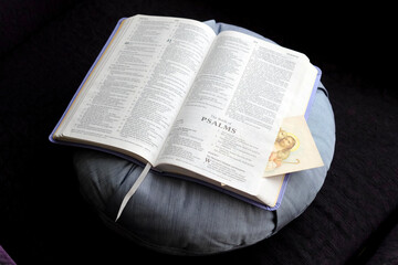 Fototapeta premium Pray at home. Open Bible with a religious image on a cushion.