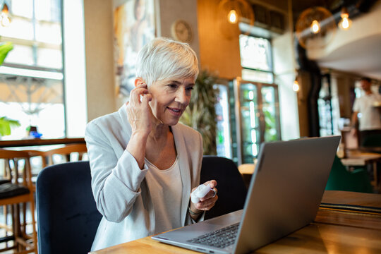 Senior businesswoman enjoying coffee while working on laptop at cafe