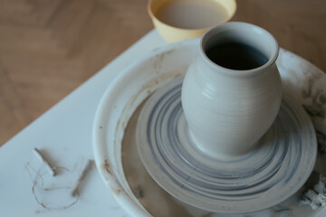Wet clay vase made by hands on pottery wheel