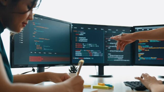 Slow motion back end software developer engineer for computer programming working together on debugging writing computing code, solving complex algorithms display on monitor in office. Burgeoning