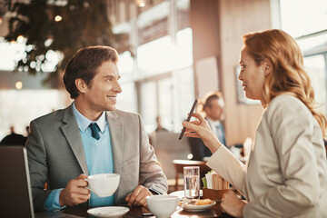 Business meeting between professional man and woman in cafe over coffee and discussion