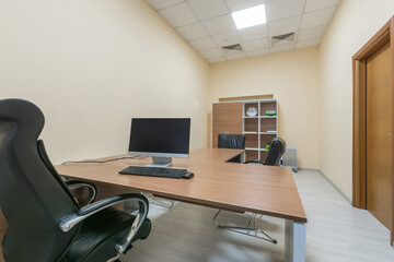 Workplace in a modern office. A monitor on the table, a filing cabinet, ergonomic chairs.