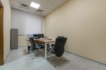 Modern office with desks and ergonomic chairs. Light decor. Blinds on the window.