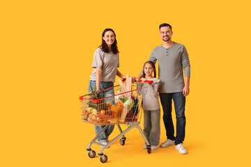 Happy family with full shopping cart on yellow background