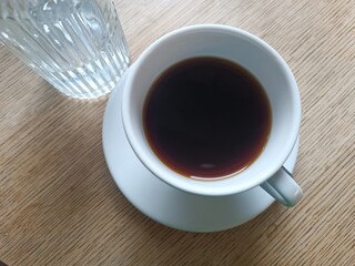 Top view white cup black coffee with water bottle wooden table. Morning routine coffee breakfast