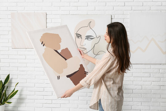 Young woman with abstract painting at art gallery exhibition